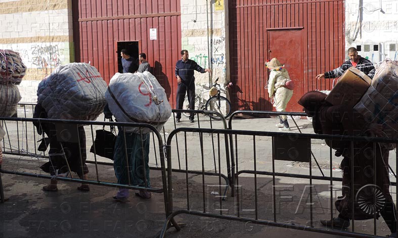 Preparación clandestina A los porteadores se les adosan los bultos a la espalda con cinta adhesiva y cuerdas. En el caso de los fardos de fuera de los polígonos, la operación se realiza a escondidas en el interior de estos almacenes. 