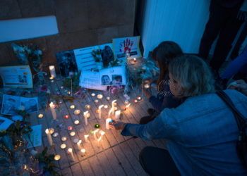 Rabat (Morocco), 22/12/2018.- A person lights candles as others hold placards during a vigil for the two Scandinavian hikers, who were killed in Morocco's High Atlas mountains, outside the Danish Embassy in Rabat, Morocco, 22 December 2018. According to media reports, four Moroccan nationals arrested on suspicion of having been involved in the deaths of two female Scandinavian tourists appear on a video as they pledge their loyalty to the Islamic State terror organization. The bodies of Maren Ueland from Norway and Louisa Vesterager Jespersen from Denmark were found nearby a village by a popular trekking area in the Atlas Mountains. (Dinamarca, Marruecos, Noruega) EFE/EPA/JALAL MORCHIDI