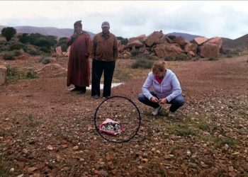 Arrodillada, María Teresa Osorio deposita un ramo sobre los restos de su tío, José Osorio Ramírez, junto con el lugareño y el taxista. Detrás, ruinas del destacamento de Hameiduch. Foto de María Teresa Osorio.