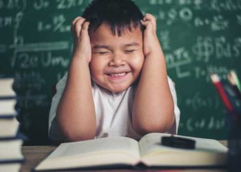 worried boy In classroom with hands on head